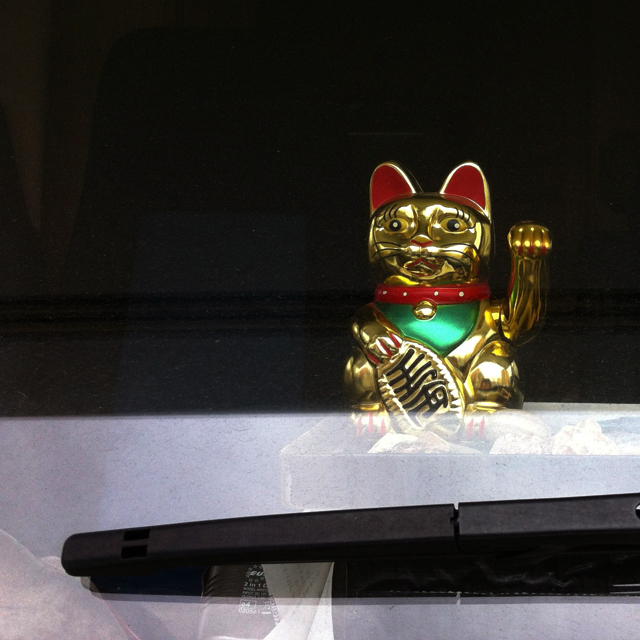 Gold lucky cat figurine on dashboard